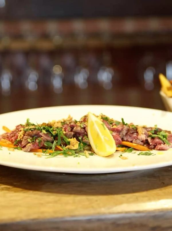 Bœuf tranché sur un lit de roquette, avec un quartier de citron